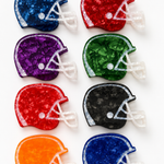Eight football helmet-shaped hair claws arranged in a 2x4 grid on a white background, each in a different color: navy, red, purple, green, maroon, black, orange, and royal blue. The items have a textured, crackled finish with white faceted details representing laces and faceguard.