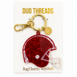 A maroon football helmet bag charm keychain by Duo Threads, attached to a gold clasp and displayed on its white backing card.