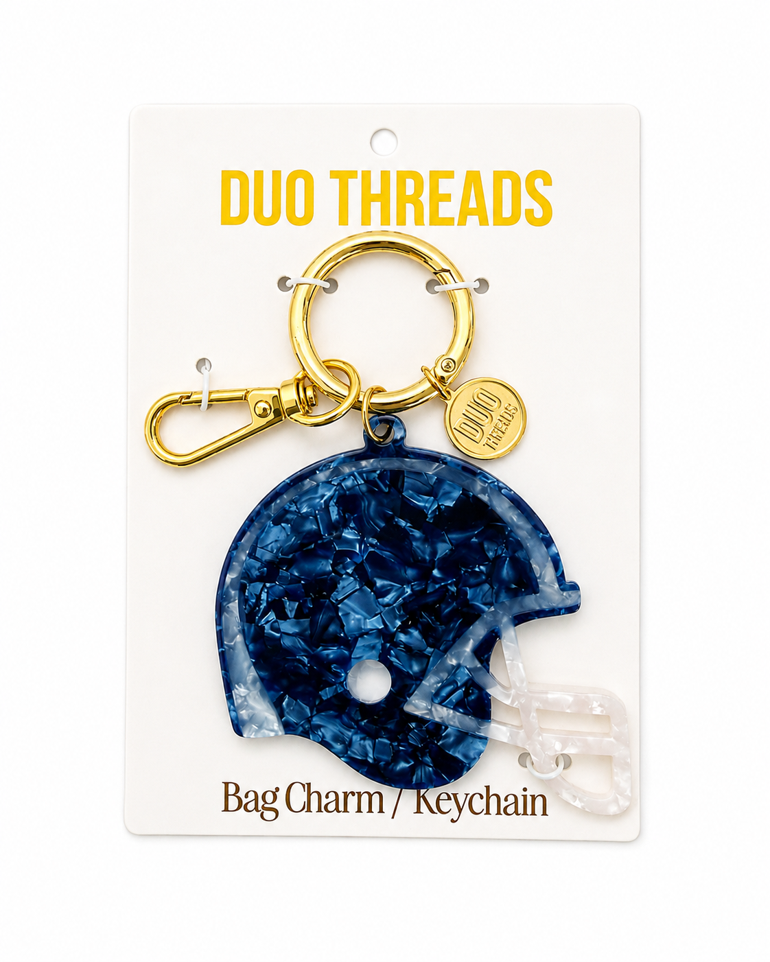 A navy blue helmet-shaped bag charm keychain with a gold clasp and a small round branded tag, mounted on a white card labeled DUO THREADS.