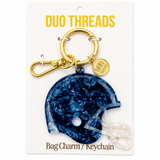A navy blue helmet-shaped bag charm keychain with a gold clasp and a small round branded tag, mounted on a white card labeled DUO THREADS.