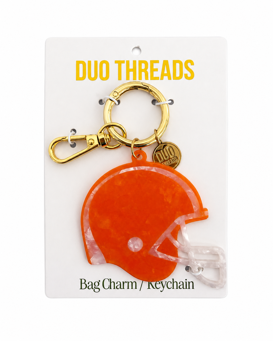 An orange helmet-shaped bag charm keychain by Duo Threads, attached to a gold clasp and a small round gold tag, displayed on a white backing card.