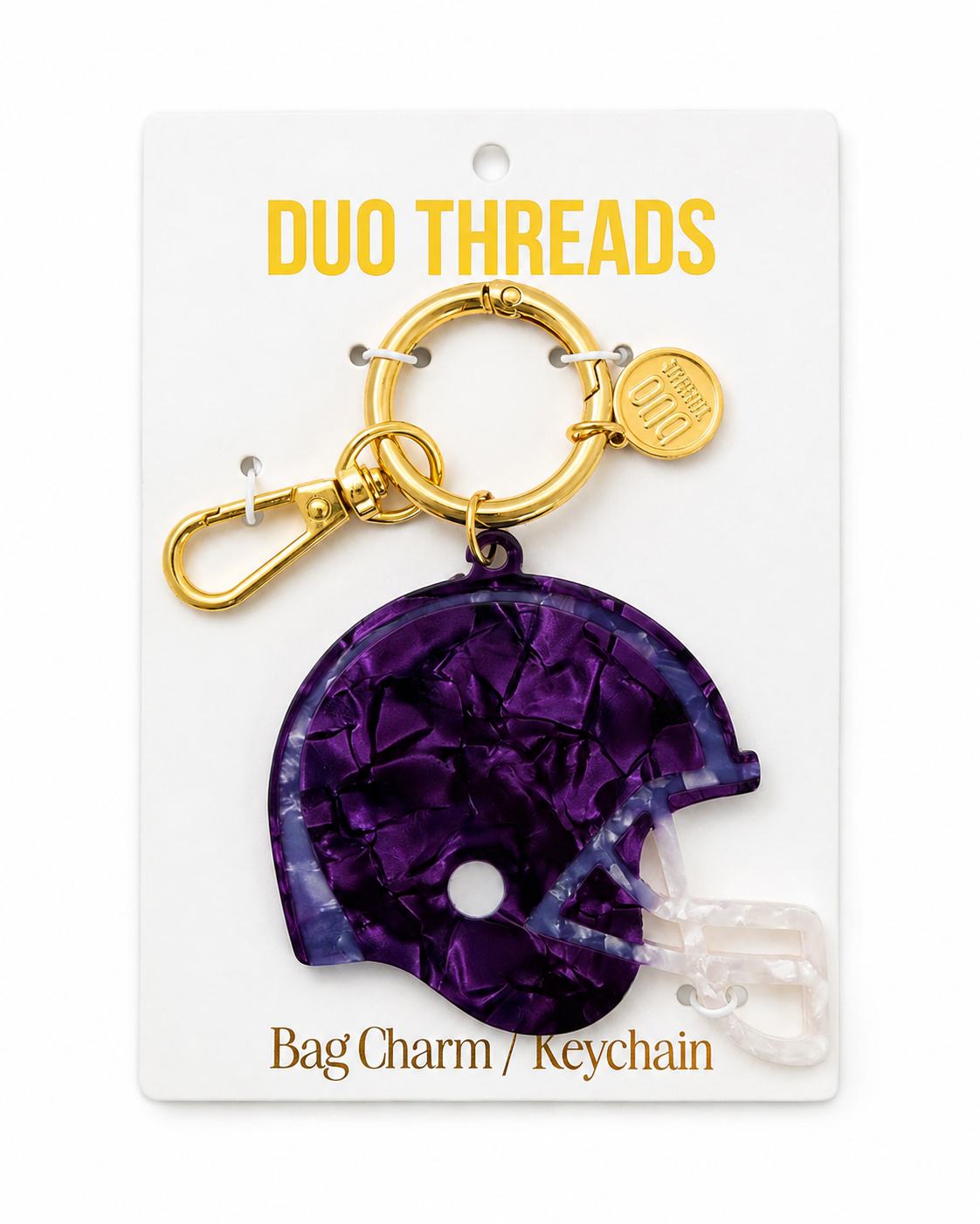 A purple football helmet bag charm keychain by Duo Threads, attached to a gold-tone split ring and clasp, displayed on its white backing card.