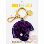 A purple football helmet bag charm keychain by Duo Threads, attached to a gold-tone split ring and clasp, displayed on its white backing card.