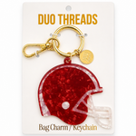A red glitter football helmet bag charm keychain by Duo Threads, attached to a gold clasp and displayed on its white retail backing card.