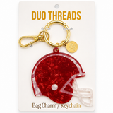 A red glitter football helmet bag charm keychain by Duo Threads, attached to a gold clasp and displayed on its white retail backing card.
