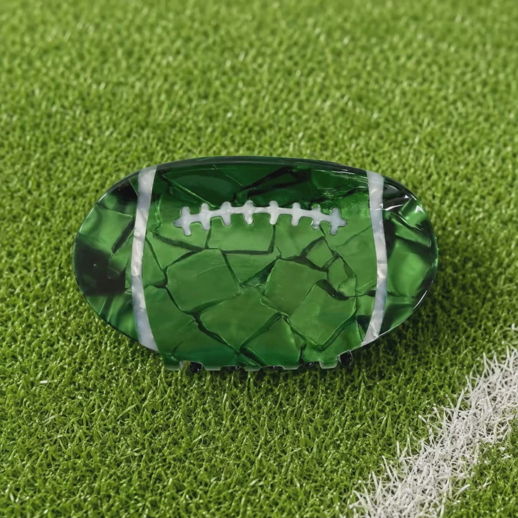 Animation rotating through the colored football shaped claw clips on green turf background